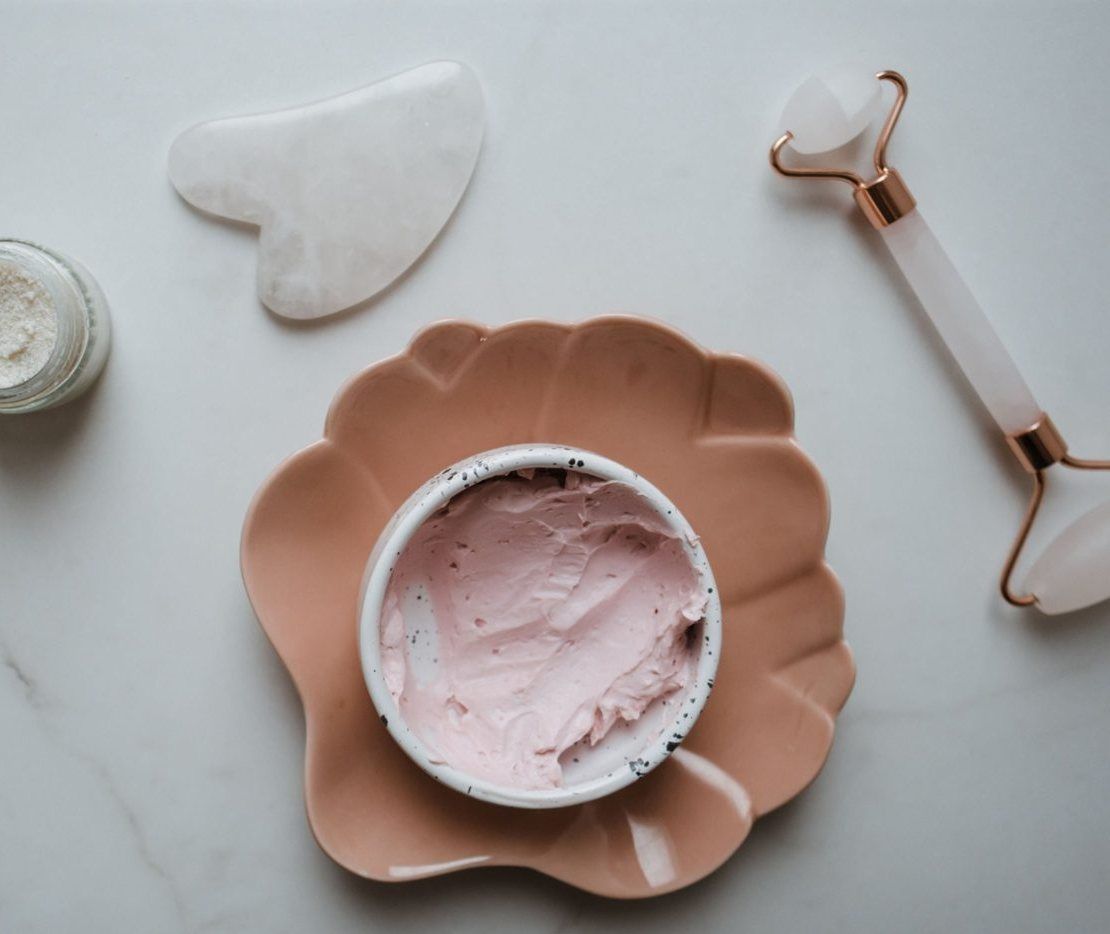 Gua-Sha-Stein und Massageroller auf hellem Marmor