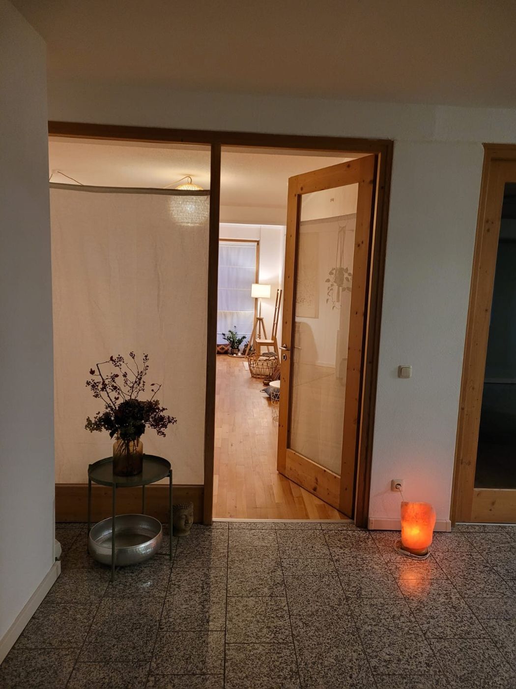 Eingangsbereich zum Behandlungsraum mit warmem Licht, Trockenblumen und Salzkristalllampe