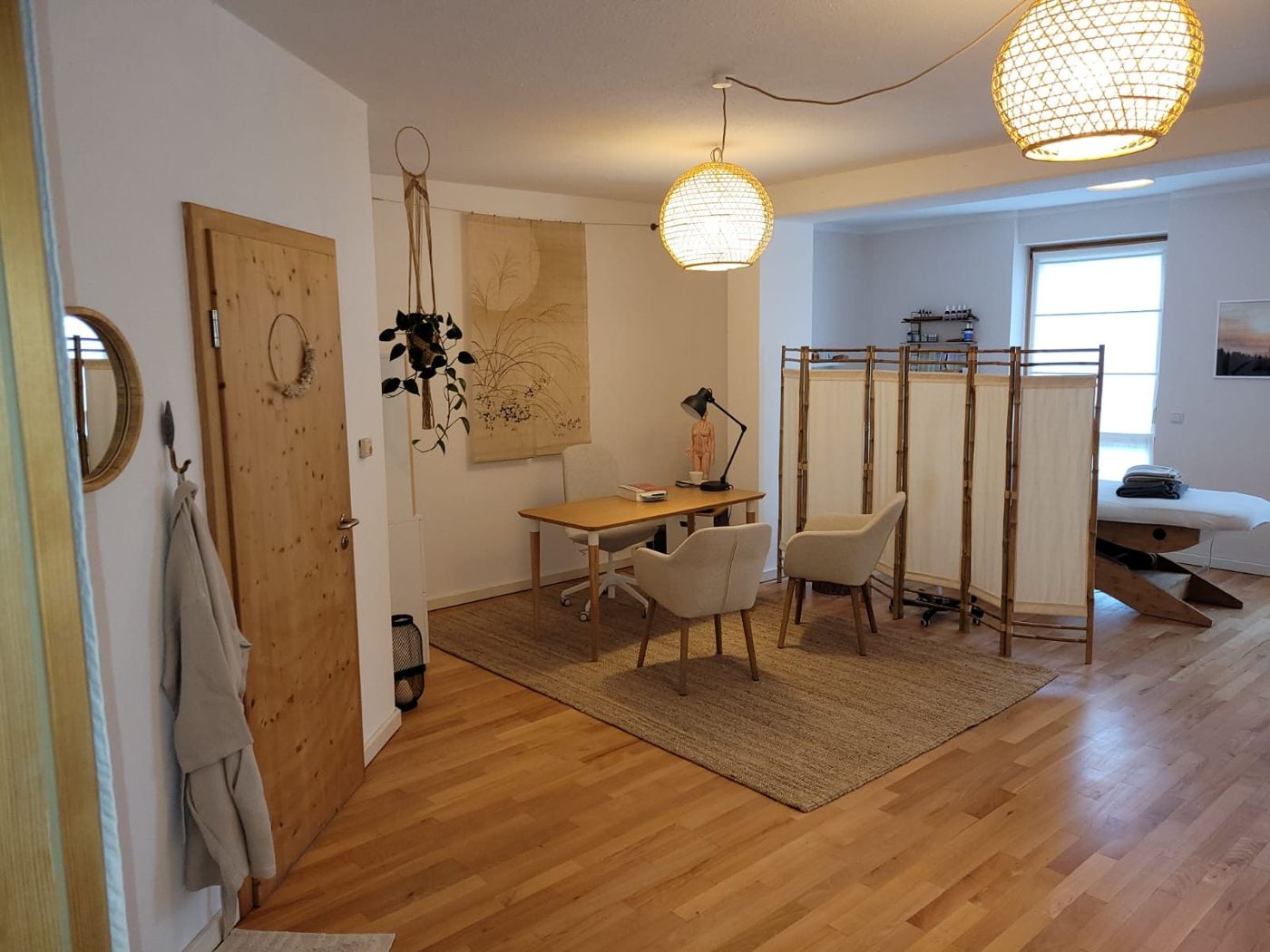 Gesprächsbereich mit Tisch, zwei Sesseln und Rattanlampen