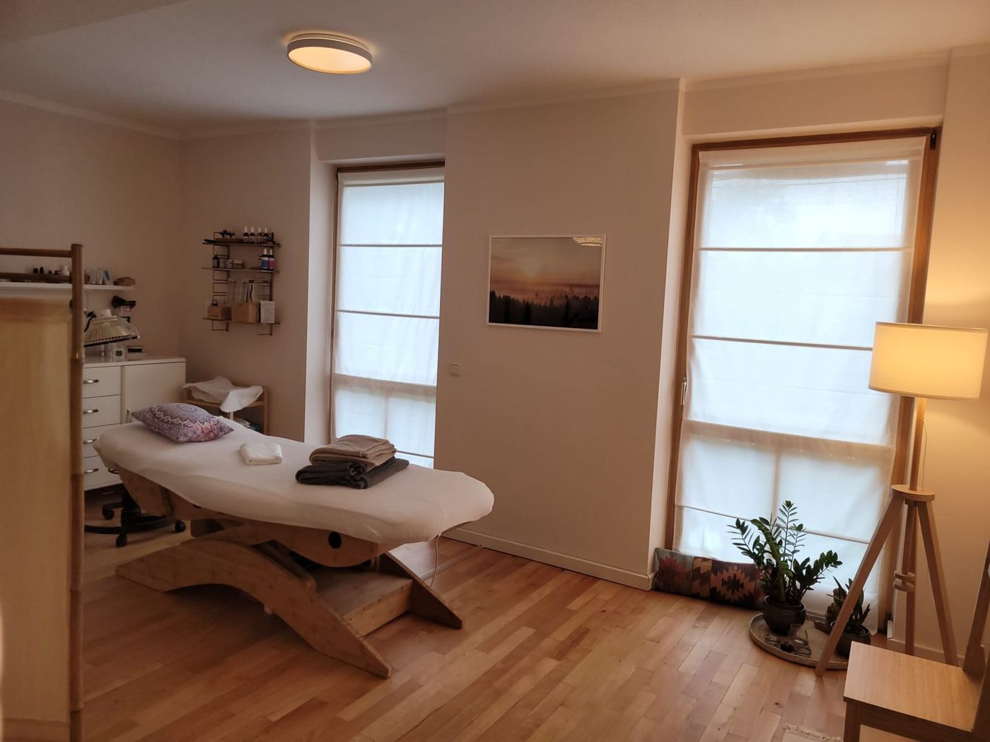 Behandlungsliege aus Holz mit Decken im hellen Behandlungsraum